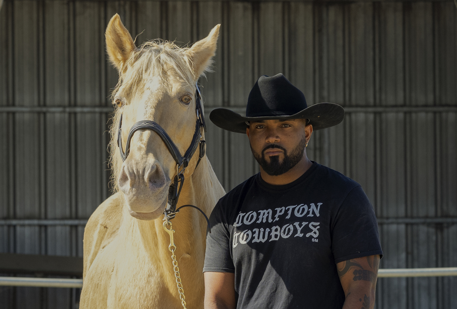 Compton Cowboys man standing next to blonde horse