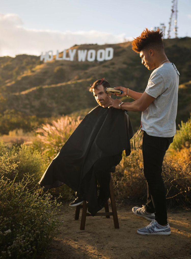 Julien Howard a.k.a. Velo Barber cutting a person's hair in the 
