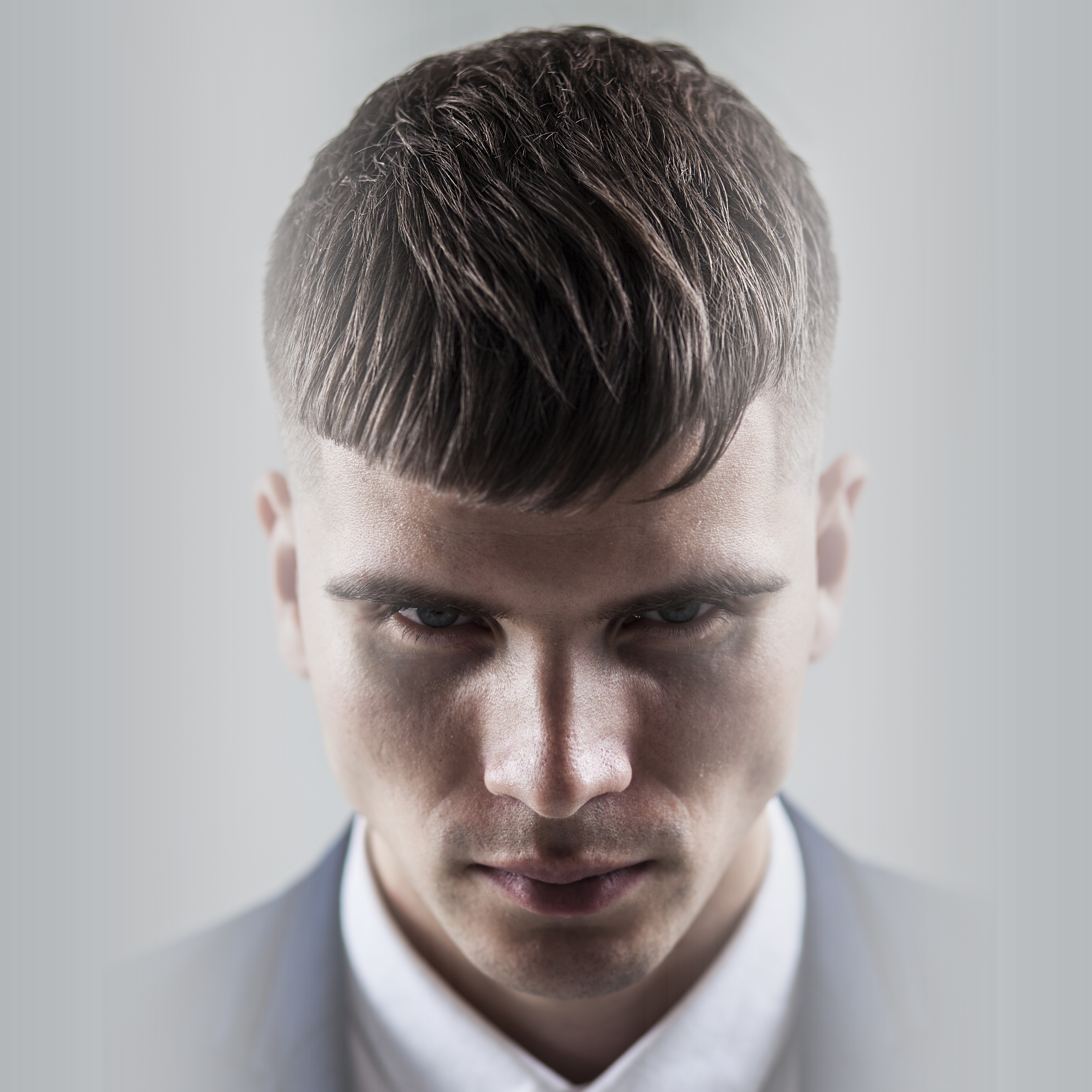 Male model wearing suit jacket and white shirt with mid-fade haircut with lightly textured crop by Andis clippers.