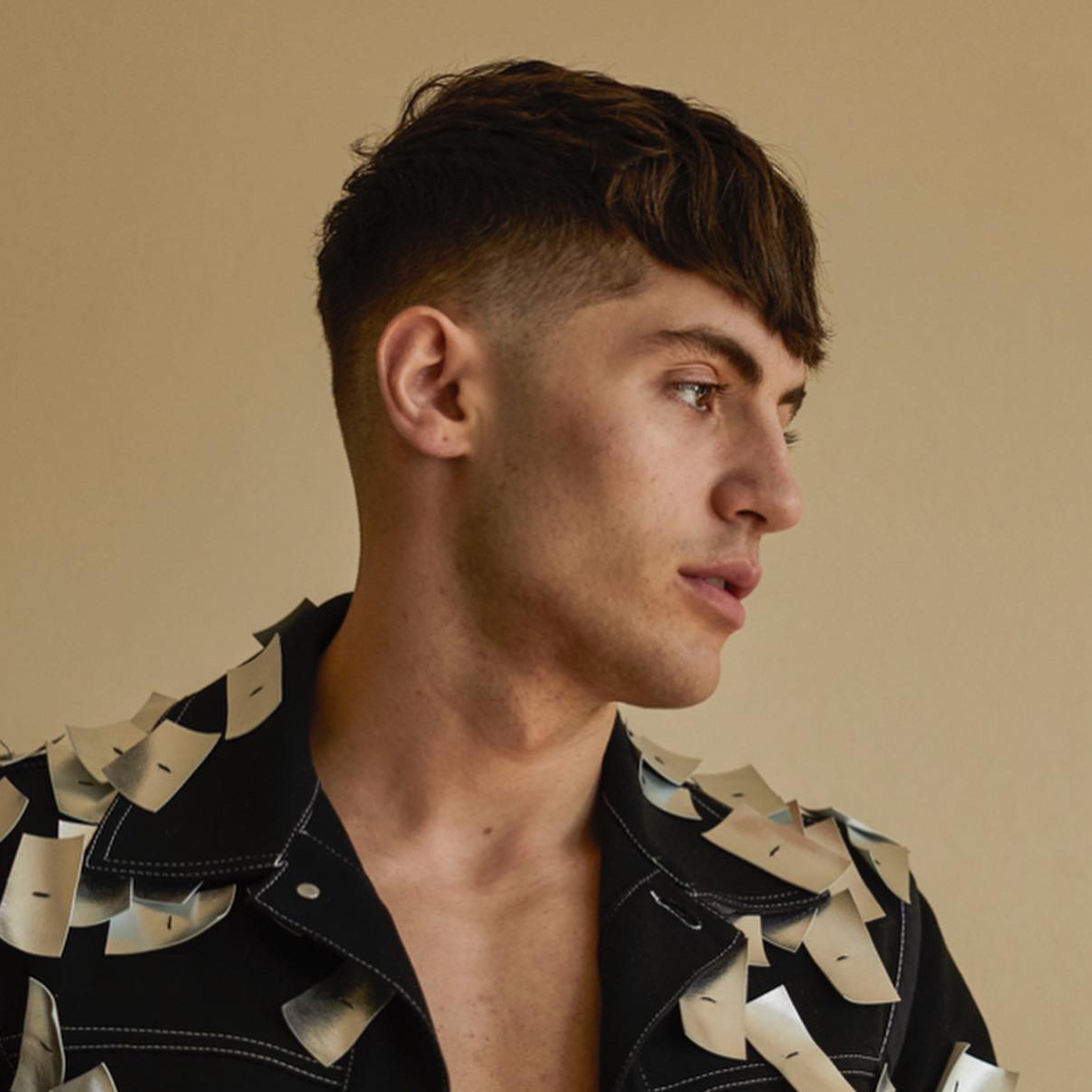 Caucasian male in artistic button-down shirt with straight bangs and mid-fade designed by Andis.