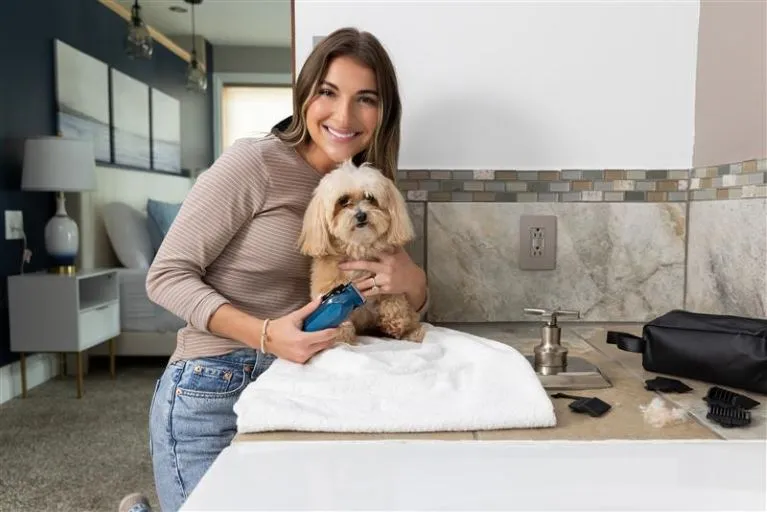 Woman cutting dogs hair in bathroom.